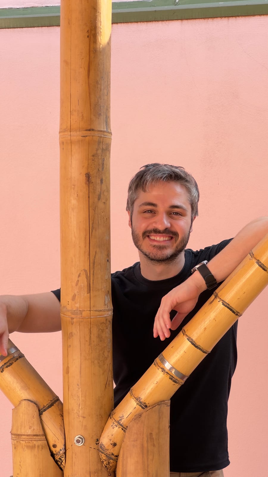 Renato Sertori sorrindo, apoiado num pilar de bambu